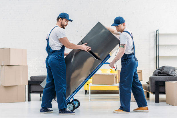 Two Movers Using Hand Truck While Transporting Refrigerator In L